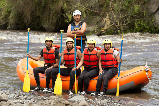 A team of athletes in white water rafting gear rowing their boat fiercely through the extreme rapids of a lake.