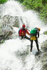 A team of adventurers in Ecuador navigate a challenging canyon while enjoying the thrill of canyoning, surrounded by lush greenery and cascading waterfalls.