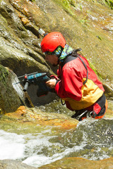 Expert instructor meticulously drilling holes for a thrilling new canyoning route at the breathtaking Chama Waterfall in Ecuador's lush wilderness.