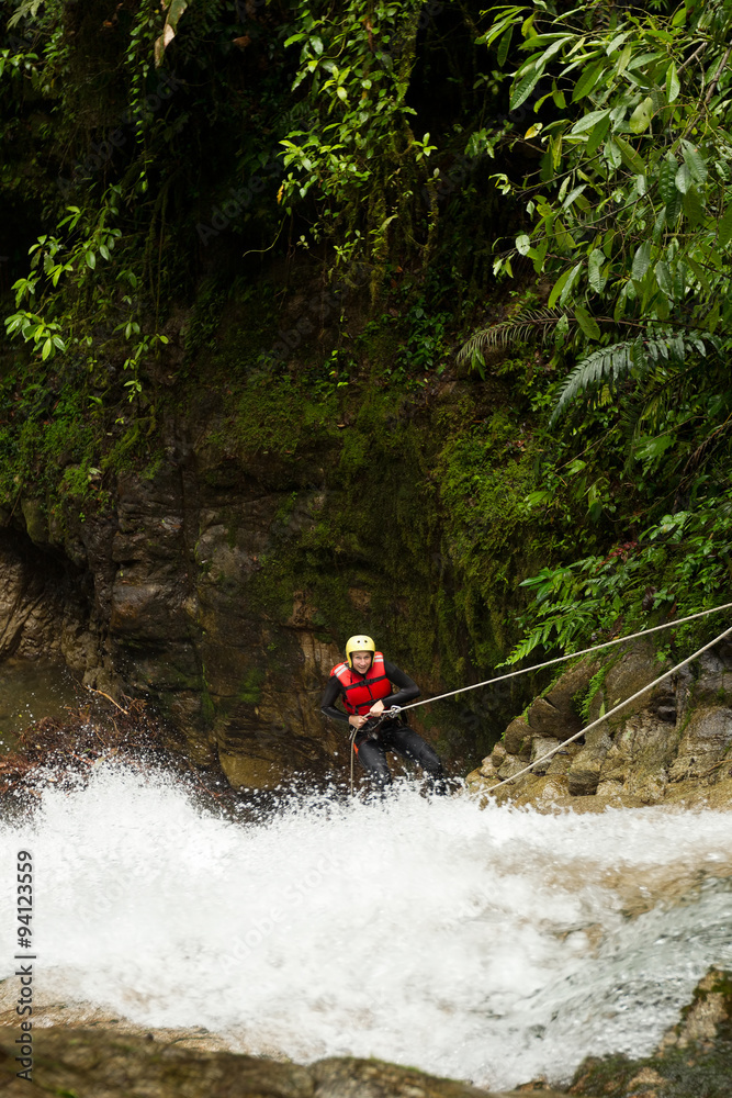 Poster Experience the thrill of adventure as you witness an adult woman clad in waterproof gear descending a majestic waterfall.