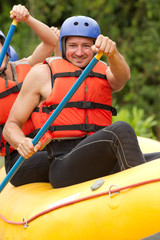 A group of people navigating through turbulent whitewater rapids on a raft, splashing and laughing as they conquer the rushing water.