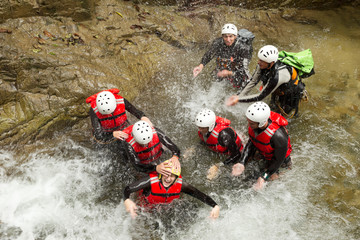 A group of adventurers gather at a stunning waterfall, ready for an exciting canyoning adventure in...