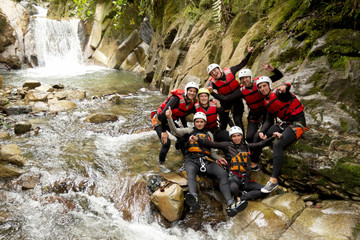 A group of active friends in helmets exploring a canyon, teaming up for an adventurous outdoor sport near a majestic waterfall.