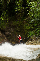 Experience the thrill of adventure as you witness an adult woman clad in waterproof gear descending a majestic waterfall.