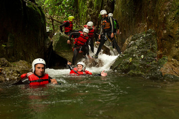 A group of adventurous individuals in harnesses navigating a canyon in the lush rainforest of Ba&ntilde;os, Ecuador, engaging in extreme canyoning activity.