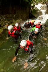 A group of friends embarking on a thrilling canyoning adventure in a national park, descending down rocky cliffs towards a majestic waterfall.