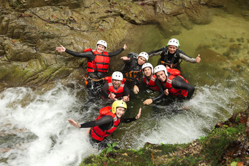 A group of young people in wet canyoning gear, exploring a river in Baños, Ecuador. They are...