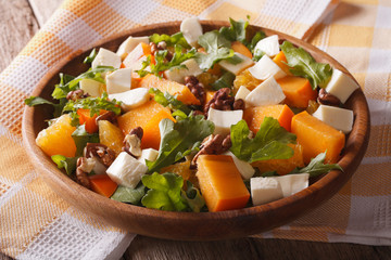 salad with persimmon, arugula, oranges and cheese. Horizontal, rustic

