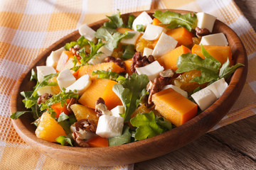 salad with persimmon, arugula, oranges and cheese close-up 
