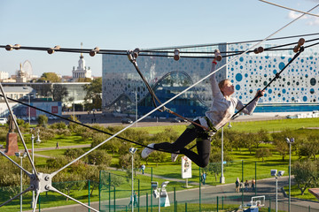 Naklejka premium Girl athlete runs an obstacle course in climbing park