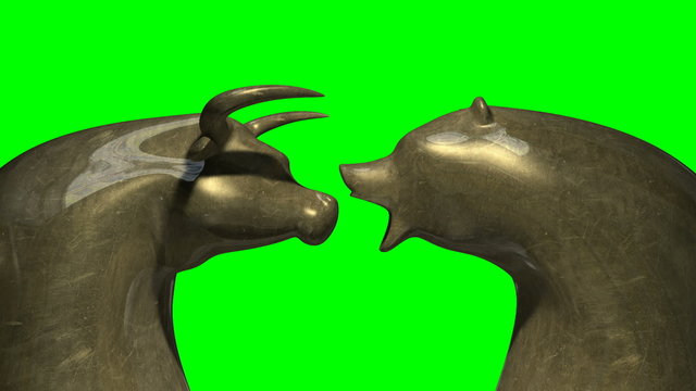 A closeup pan of two bronze castings depicting a stylized bull and a bear head in contrasting light representing a financial market trends on a green screen background