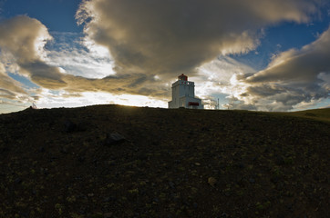 Lighthouse at Dyrholaey rock at sunset with dramatic sky