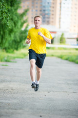 Sporty man jogging in city street park. Outdoor fitness.