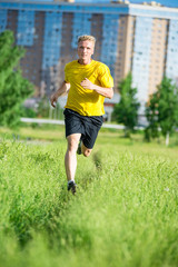 Sporty man jogging in city street park. Outdoor fitness.