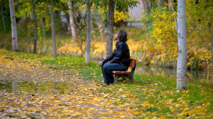 Naklejka na ściany i meble man smoking on a bench in autumn