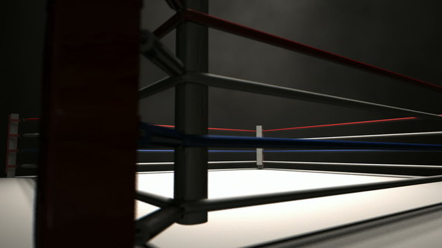 A pan across a empty regular boxing ring surrounded by ropes spotlit in the middle on an isolated dark background