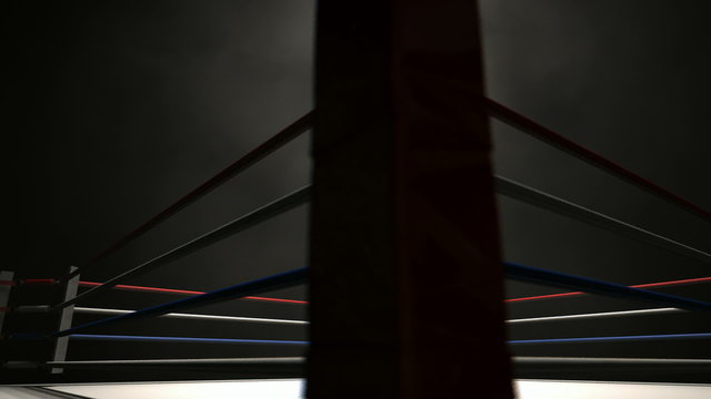 A pan across a empty regular boxing ring surrounded by ropes spotlit in the middle on an isolated dark background