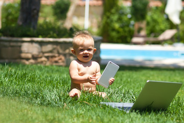 Cute baby  playing with laptop outdoors on green grass