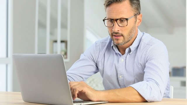Handsome 40-year-old man at home using laptop