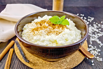 Rice porridge with cinnamon in bowl on board