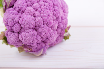 large purple cauliflower on a white wooden background, high-key, top and side views