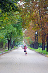 little girl with umbrella on street autumn season