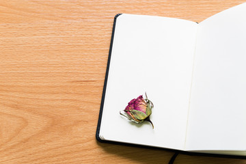Open Notebook With Dry Rose On Wooden Table With Copy Space