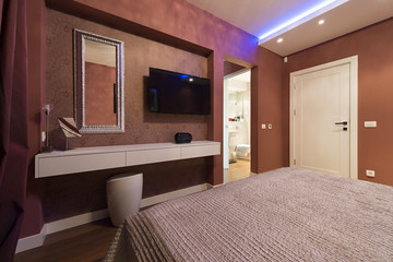Fototapeta premium Bedroom interior with wall mounted and a view to a bathroom