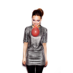 Fashion Beauty Girl blowing a red balloon. Gorgeous Woman Portrait