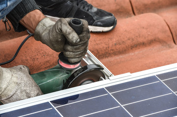 Obraz premium man on roof cuting aluminium with grinder during solar panel in