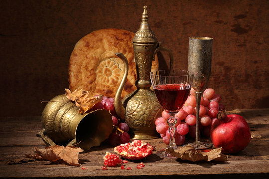Still-life in east style with grapes, a pomegranate and a jug