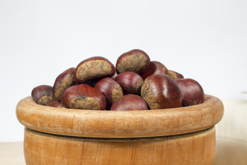 Close-up of wooden bowl full of chestnuts in front of a sack of chestnut flour