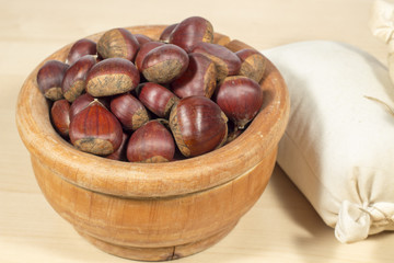 Wooden bowl full of chestnuts beside a small sack of chestnut flour