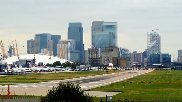 Airplane taking off from City airport in London with skyscrapers in the background
