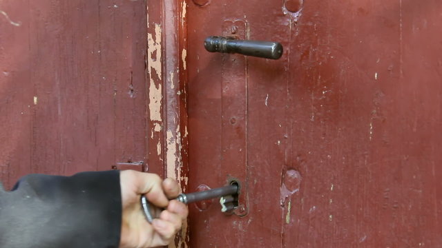 Man Opens An Old Wooden Door With A Huge Iron Key