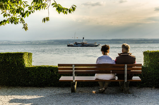Älteres Paar auf Bank mit Blick auf See und Dampfer