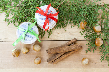 Christmas cookies with ribbons, apples, nuts, cones, cinnamon and green arborvitae branch on a wooden table.