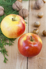 Christmas sweets, apples, nuts and green arborvitae branch on a wooden table