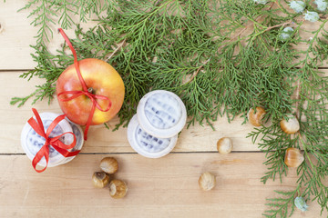 Christmas sweets, apples, nuts and green arborvitae branch on a wooden table