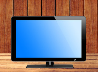 Modern TV screen with blue screen on wooden table