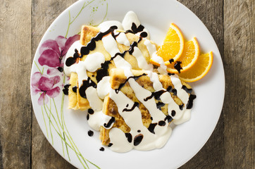 Sweet pancakes with sour cream and chocolate on wooden table