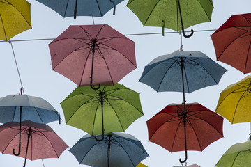 Fototapeta na wymiar Hanging Multicoloured umbrellas over blue sky Colourful umbrellas urban street decoration