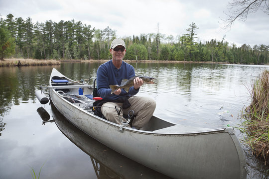 Fisherman in a canoe on a lake shows a walleye
