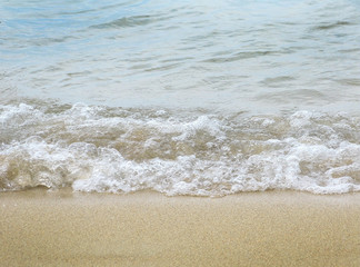 Fototapeta na wymiar Sandy beach wave. Wave slaps onto shore on soft sand in Mallorca, Balearic islands, Spain in August.