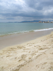 Fototapeta na wymiar Sandy beach with turquoise water and dark skies in Mallorca, Balearic islands, Spain in August.