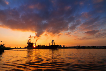 Fototapeta na wymiar Silhouette of a big cargo ship and industry at sunset in IJmuiden in the Netherlands