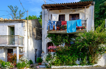 A beautiful greek house up a hill surrounded wirh blooming flowers, Corfu, Greece.