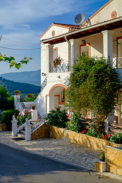 A beautiful greek house up a hill surrounded wirh blooming flowers, Corfu, Greece.
