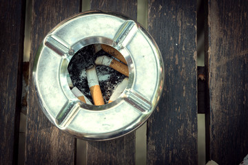 cigarette butt in ashtray, stainless ashtray on wood table