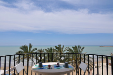 Chairs with a table on the balcony overlooking the sea
